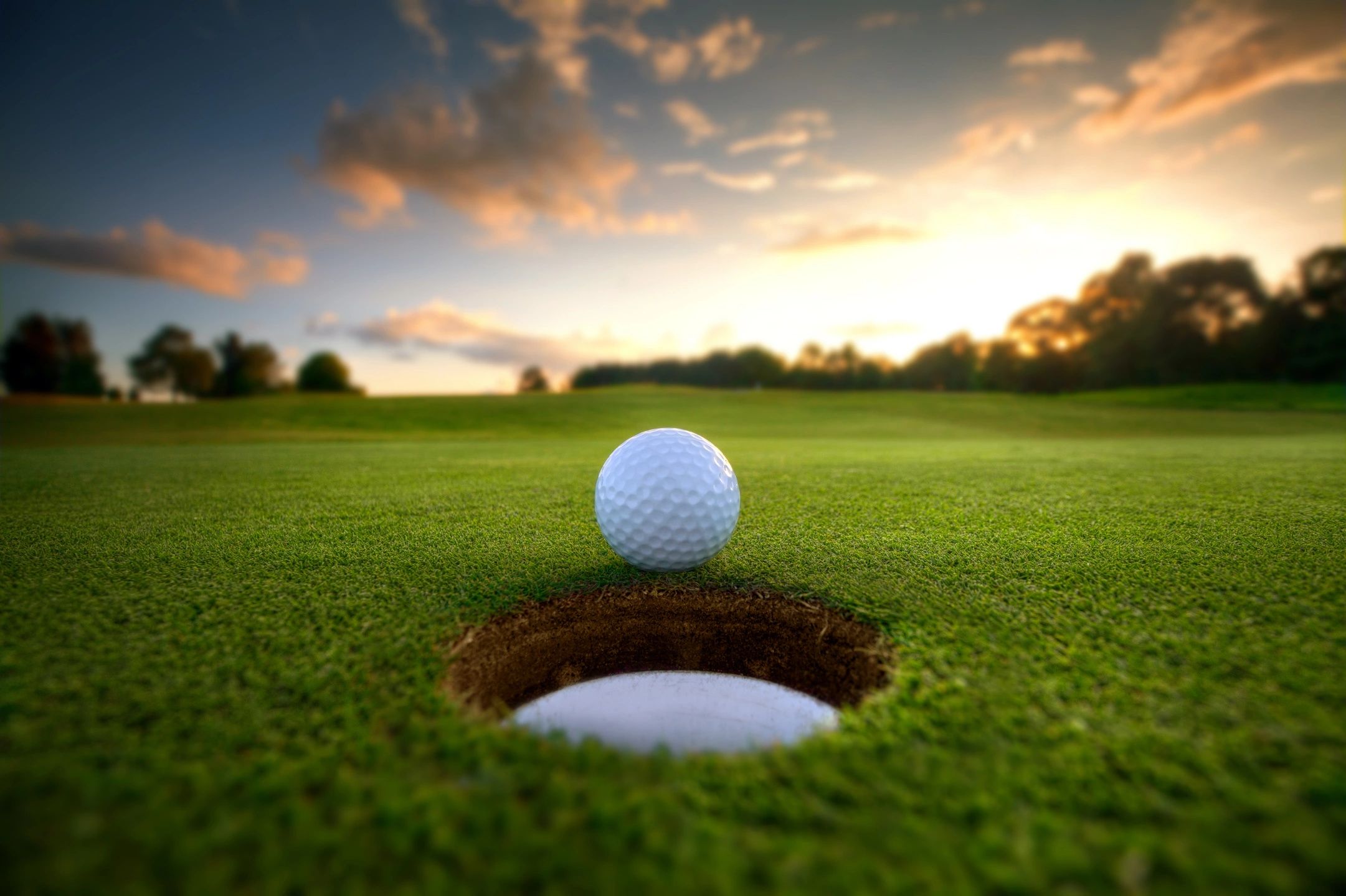 Golf ball rolling into cup