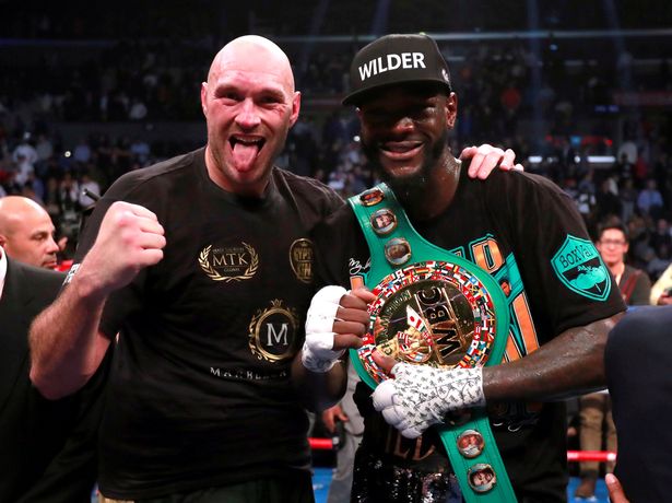 Deontay Wilder standing with Tyson Fury