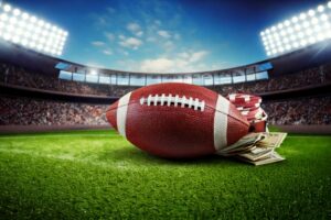 A football laying in a stadium with money laying beside it. Indicating gambling